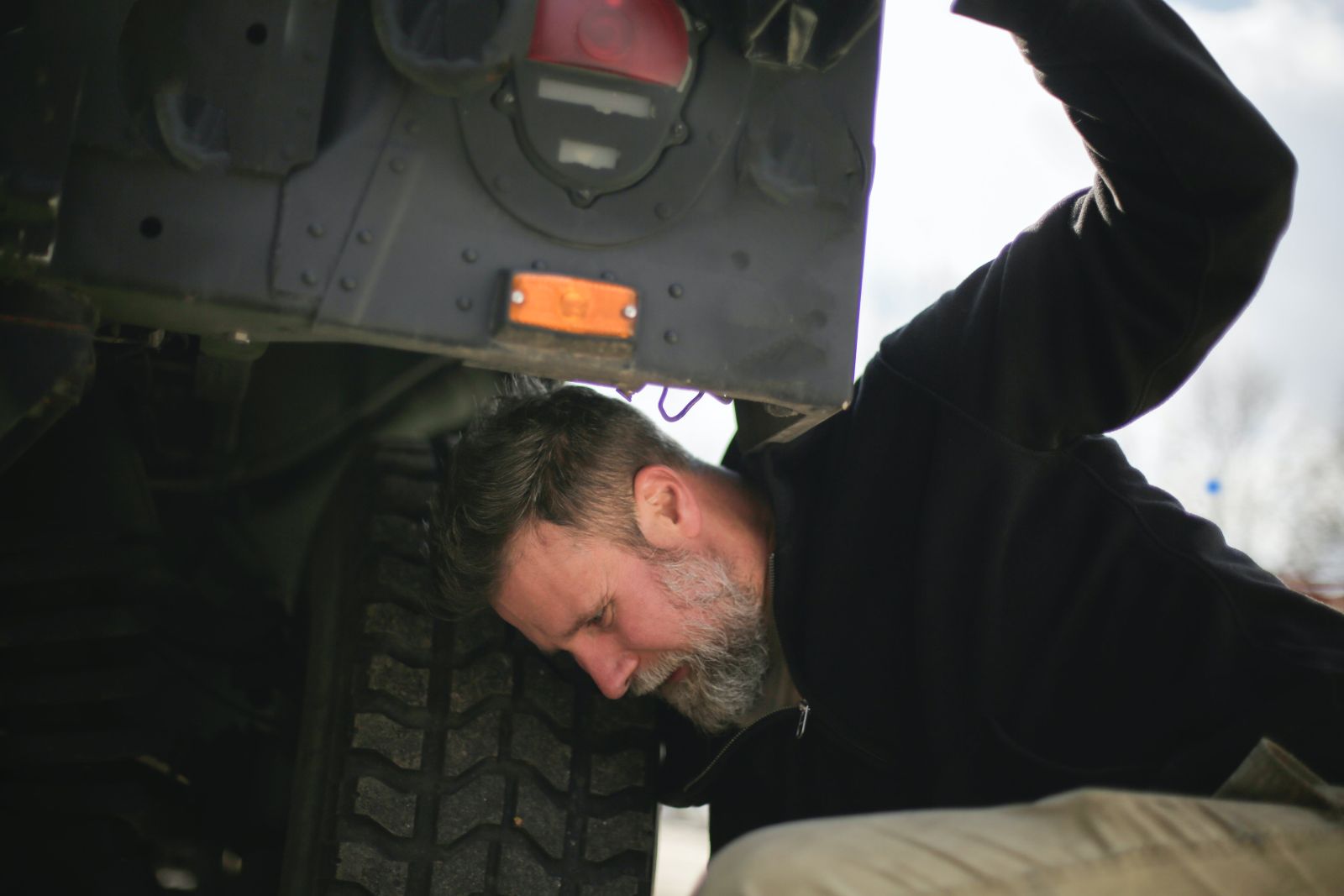 A man checking for signs of deteriorations on his car's suspension control arms.