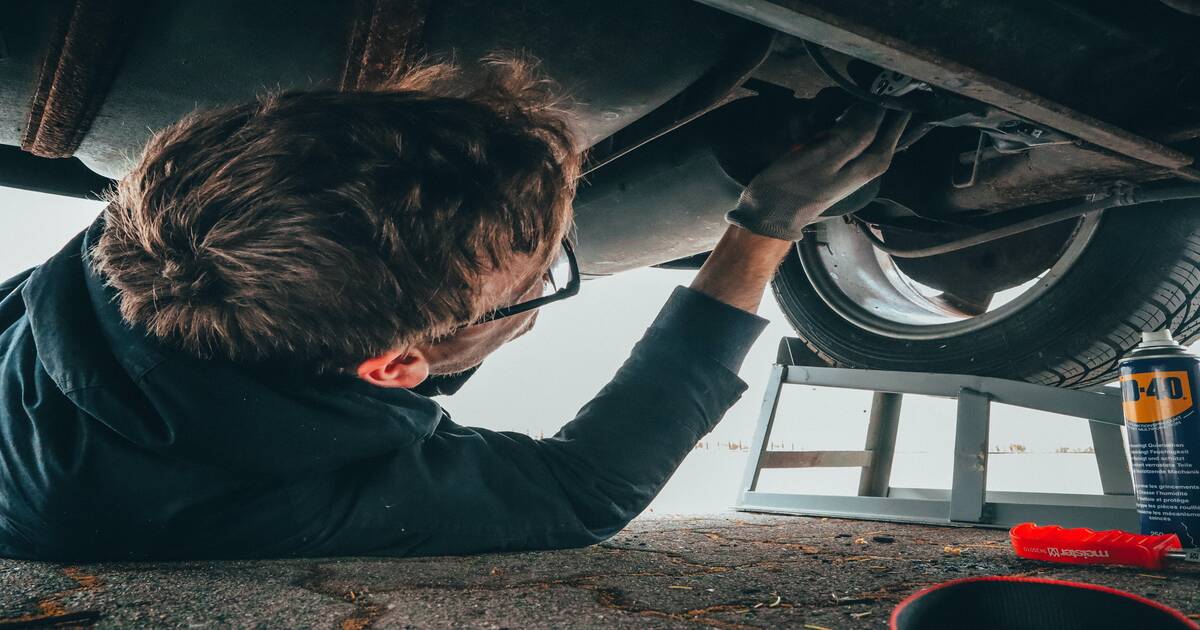 A person doing maintenance on a car with an aftermarket exhaust system.