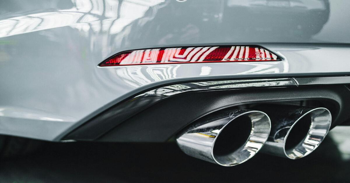 A close-up image of a muffler on a grey car.