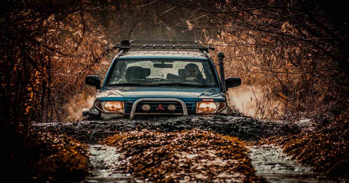 A car with a snorkel driving over a hill.