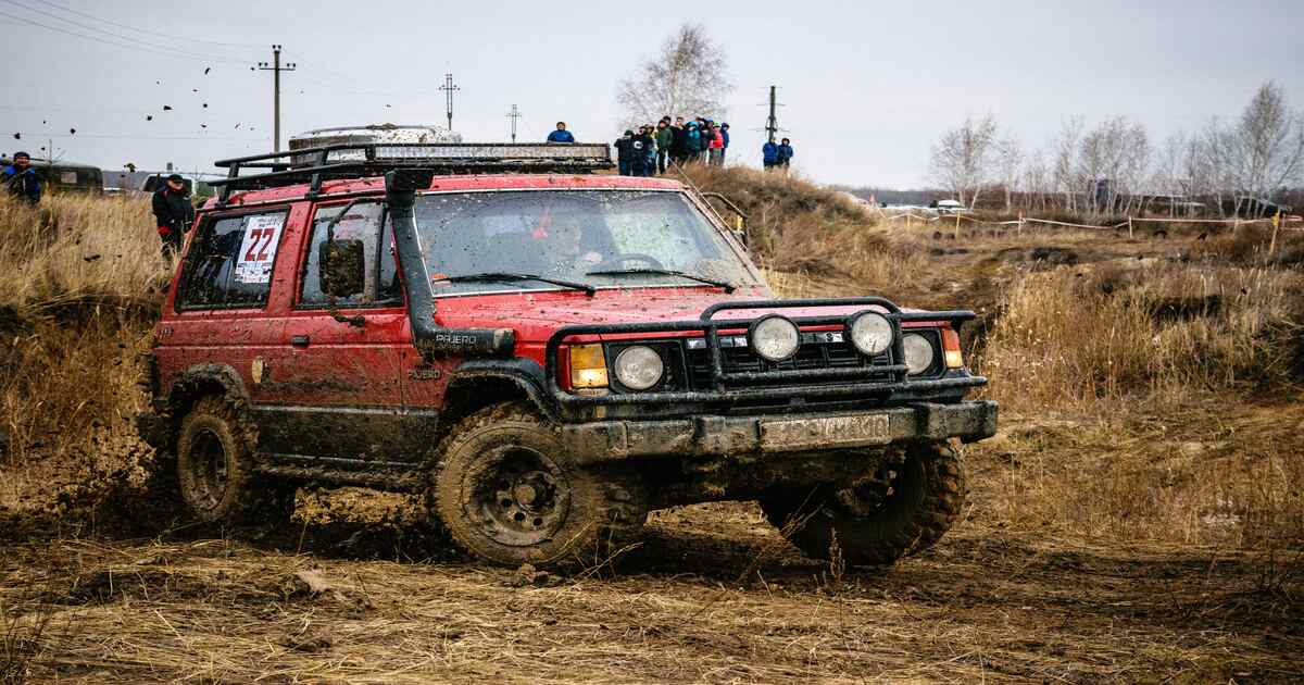 A red SUV with a snorkel on a mud track.
