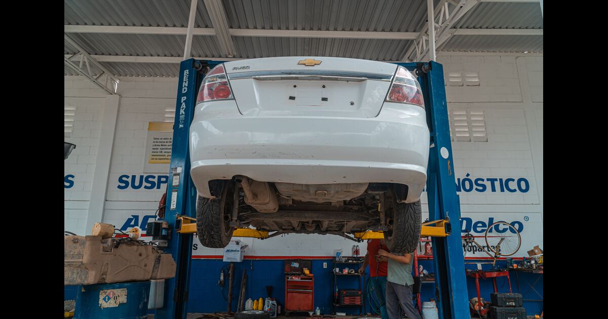 A white car in a repair shop checking suspension struts and shocks.